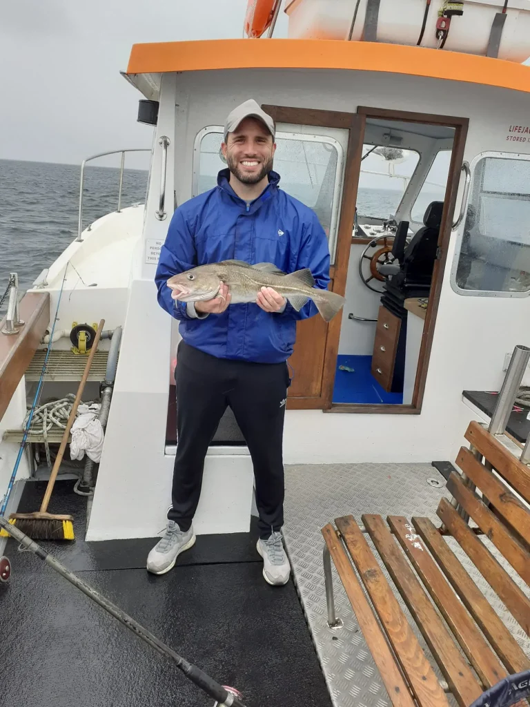 Angler beside the wheelhouse with a fish