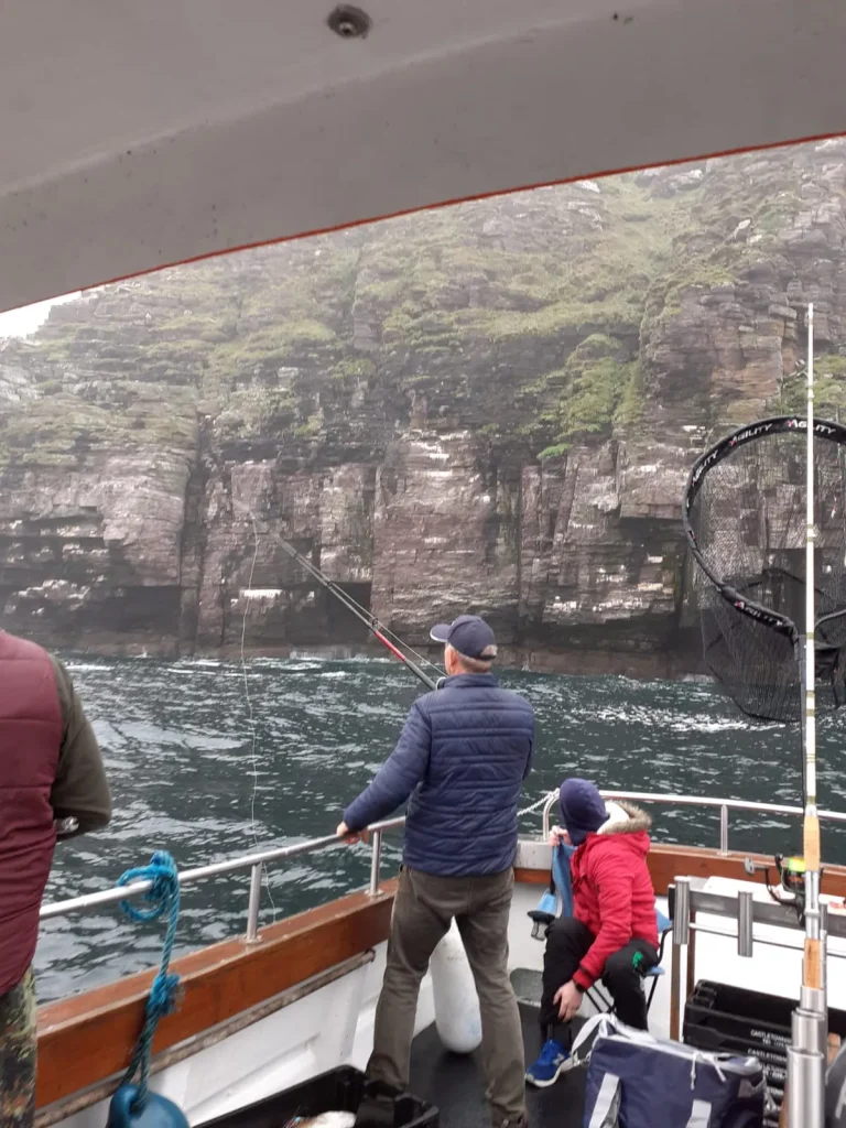 Anglers fishing under high sea cliffs